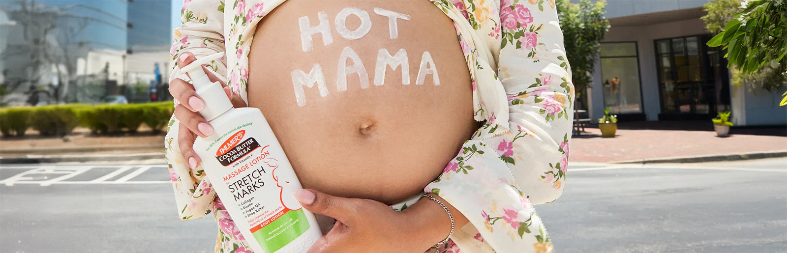 Pregnant woman with Hot Mama written on belly holding bottle of Palmer's Massage Lotion for Stretch Marks