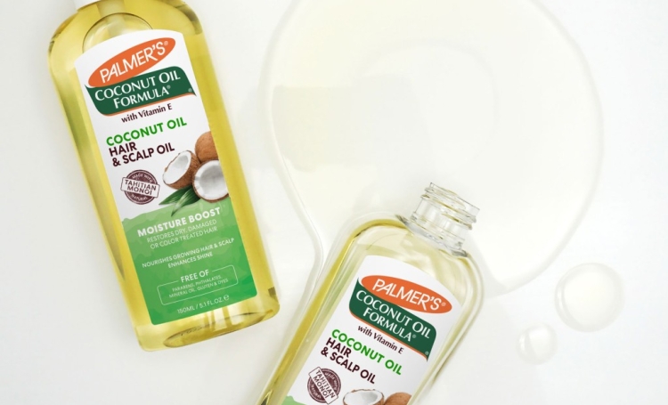 Palmer's Coconut Oil Hair & Scalp Oil bottles for hair slugging being spilled on table